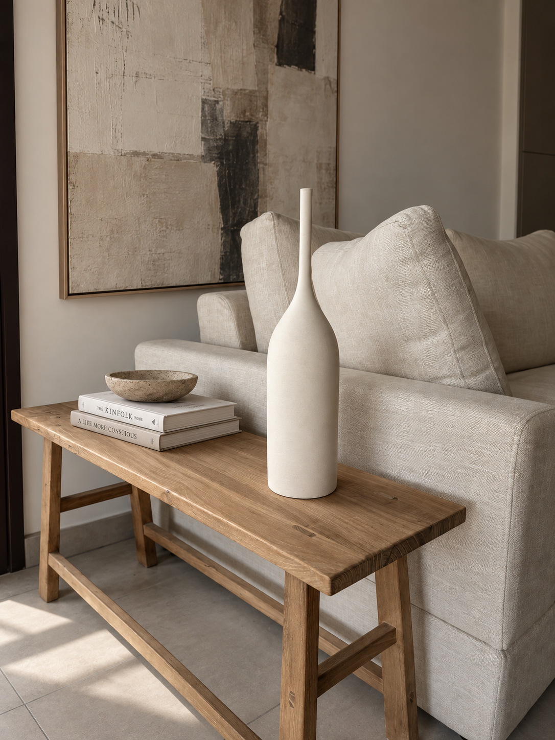 Sculptural vessel, textured artwork and tactile objects on an oak table